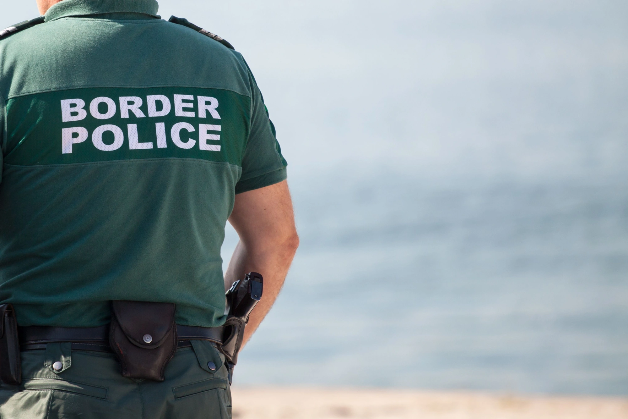 Border police officer looking out over a field