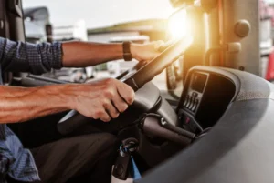 CDL driver with his hands on the wheel of a semi-truck