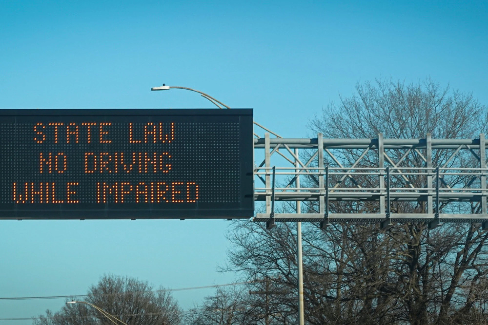 An overhead highway sign that says state law no driving while impaired