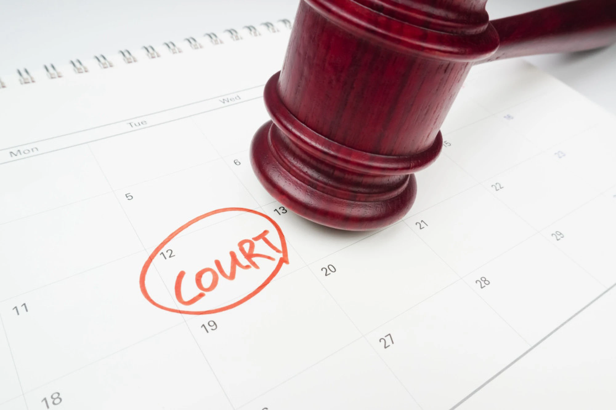 A judge’s gavel resting on a calendar with a date labeled “court.”