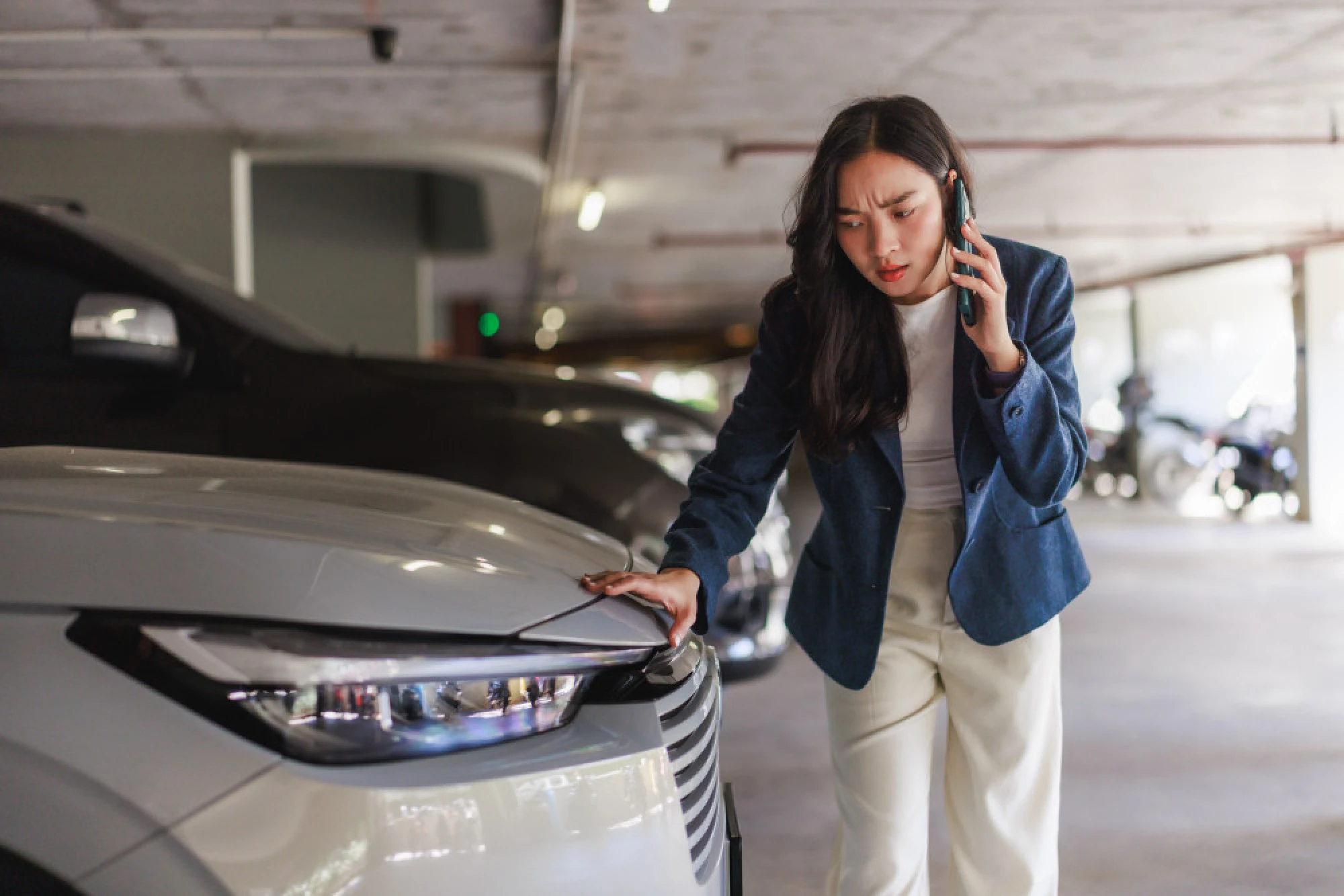 A woman reviewing the damage on her car in a parking garage
