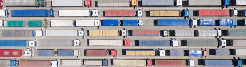 Overhead view of tens of multicolored trucks waiting for a border control checkpoint.