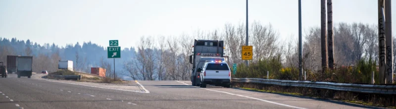 A big rig that has been pulled over by a police officer