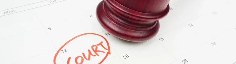 A judge’s gavel resting on a calendar with a date labeled “court.”