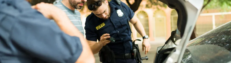 two police officers searching the trunk of a motorist’s car.