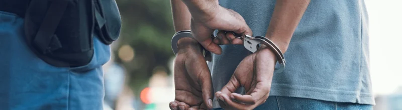 A man being led away in handcuffs by a police officer