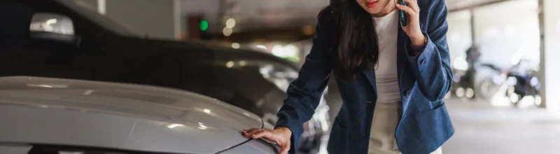 Una mujer que examina los daños que ha sufrido su coche en un aparcamiento